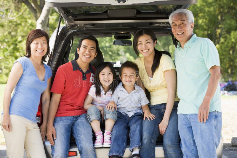 Famiglia allargata che si siede in sportello posteriore dell'automobile immagini stock libere da diritti Famiglia allargata che si siede in sportello posteriore dell'automobile immagini stock libere da diritti