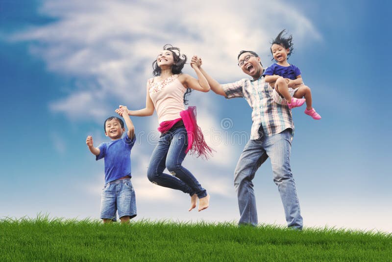 Famiglia asiatica felice in prato fotografie stock libere da diritti Famiglia asiatica felice in prato fotografie stock libere da diritti