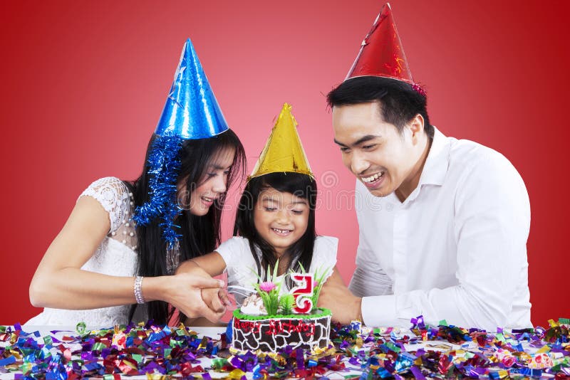 Famiglia attraente che taglia una torta di compleanno fotografie stock libere da diritti Famiglia attraente che taglia una torta di compleanno fotografie stock libere da diritti