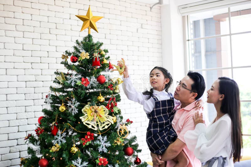 Famiglia che decorano un albero di Natale e padre che dà il Natale G immagine stock Famiglia che decorano un albero di Natale e padre che dà il Natale G immagine stock
