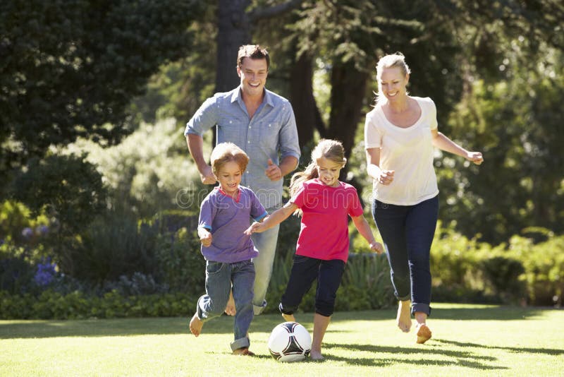 Famiglia che gioca a calcio nel giardino insieme fotografia stock Famiglia che gioca a calcio nel giardino insieme fotografia stock