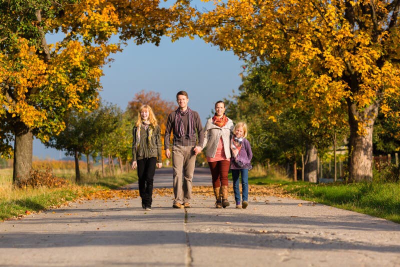 Famiglia che ha passeggiata davanti agli alberi variopinti nell'autunno immagini stock libere da diritti Famiglia che ha passeggiata davanti agli alberi variopinti nell'autunno immagini stock libere da diritti