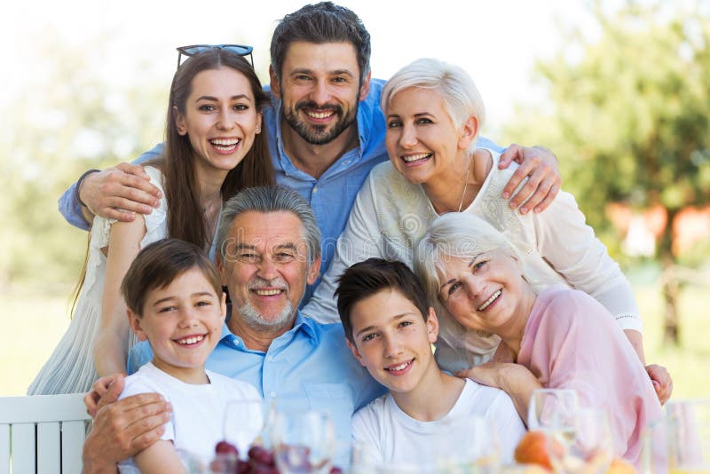 Famiglia che si siede alla tavola all'aperto, sorridendo fotografia stock libera da diritti Famiglia che si siede alla tavola all'aperto, sorridendo fotografia stock libera da diritti