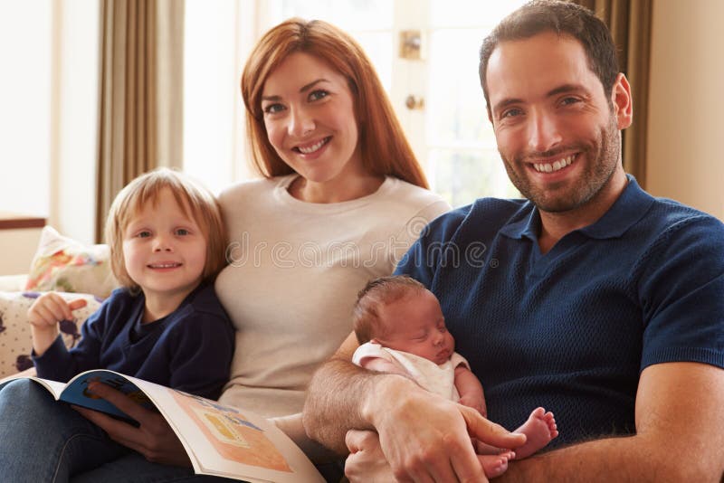 Famiglia che si siede su Sofa With Newborn Baby fotografia stock Famiglia che si siede su Sofa With Newborn Baby fotografia stock