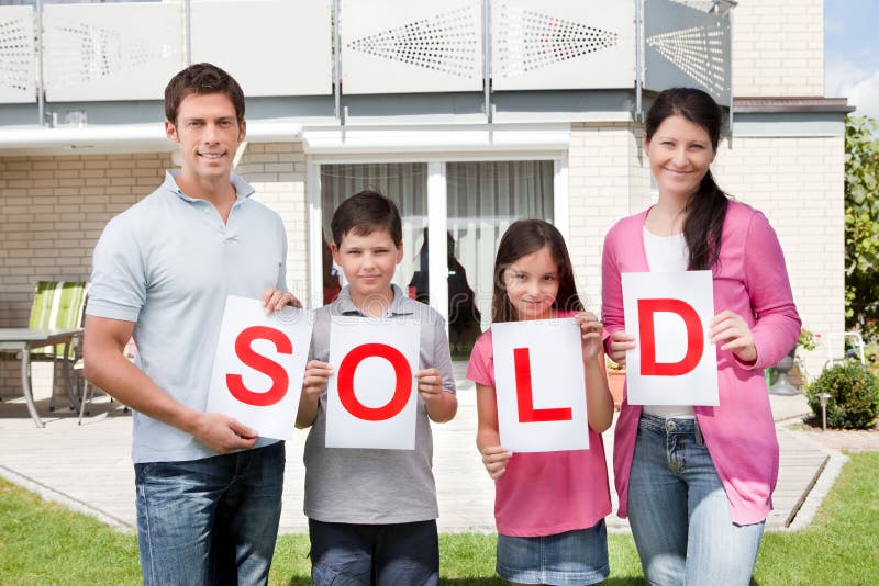 Famiglia che tiene un segno venduto fuori della loro casa immagini stock libere da diritti Famiglia che tiene un segno venduto fuori della loro casa immagini stock libere da diritti
