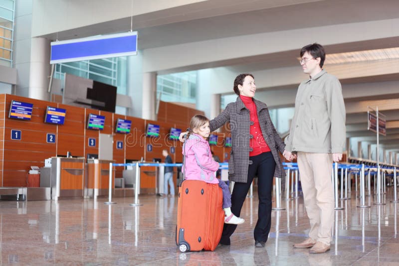 Famiglia con la valigia che si leva in piedi nel corridoio dell'aeroporto immagine stock libera da diritti Famiglia con la valigia che si leva in piedi nel corridoio dell'aeroporto immagine stock libera da diritti