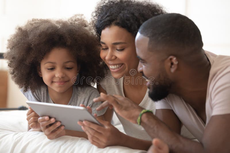 Famiglia di colore felice che usa il tablet digitale immagini stock Famiglia di colore felice che usa il tablet digitale immagini stock