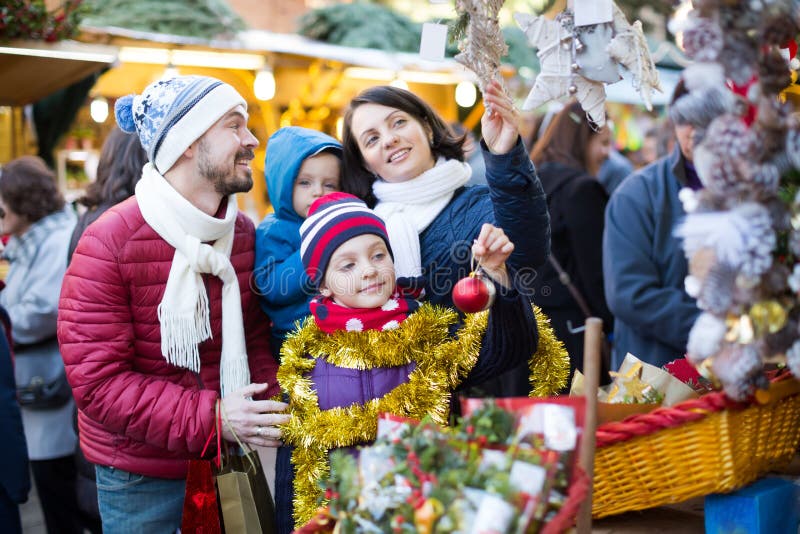 Famiglia di quattro affascinante che compra le decorazioni di feste immagine stock Famiglia di quattro affascinante che compra le decorazioni di feste immagine stock