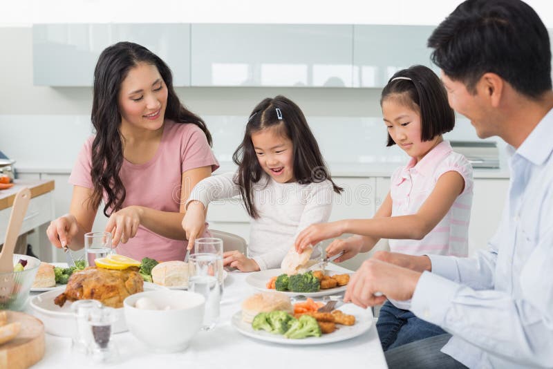 Famiglia di quattro che gode del pasto sano in cucina fotografia stock Famiglia di quattro che gode del pasto sano in cucina fotografia stock