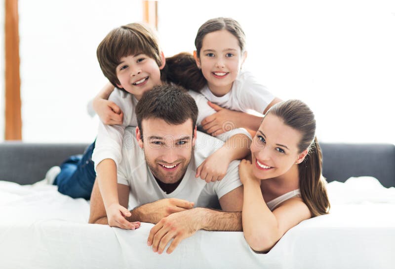 Famiglia di quattro che si trova sul letto fotografia stock libera da diritti Famiglia di quattro che si trova sul letto fotografia stock libera da diritti