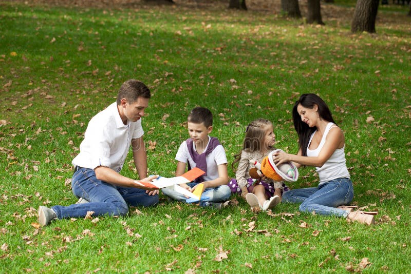 Famiglia di quattro felice, riposante nel parco di autunno fotografia stock libera da diritti Famiglia di quattro felice, riposante nel parco di autunno fotografia stock libera da diritti