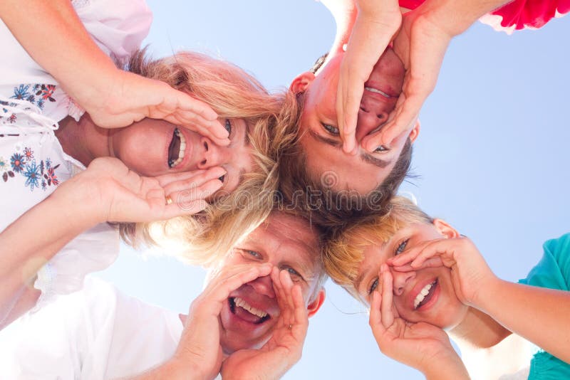 Below angle of happy family looking and shouting at camera. Below angle of happy family looking and shouting at camera