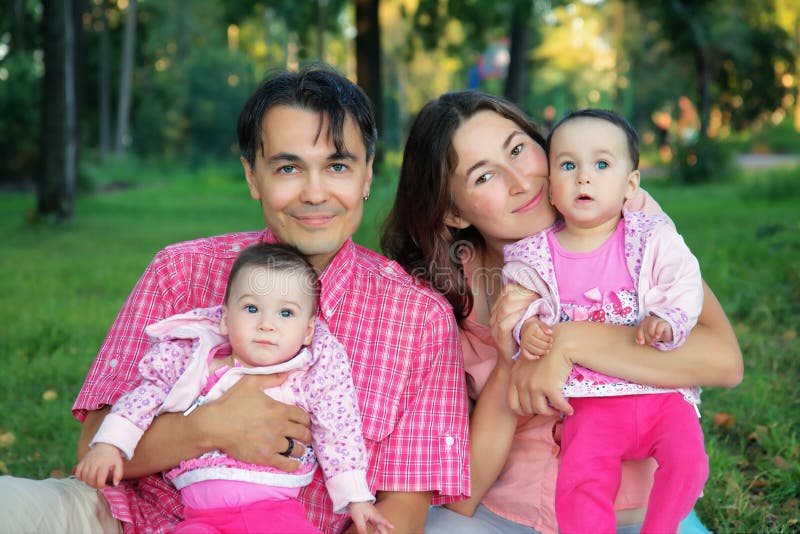 Famiglia felice al parco con il padre, la madre ed il bambino dei gemelli - s fotografia stock libera da diritti Famiglia felice al parco con il padre, la madre ed il bambino dei gemelli - s fotografia stock libera da diritti
