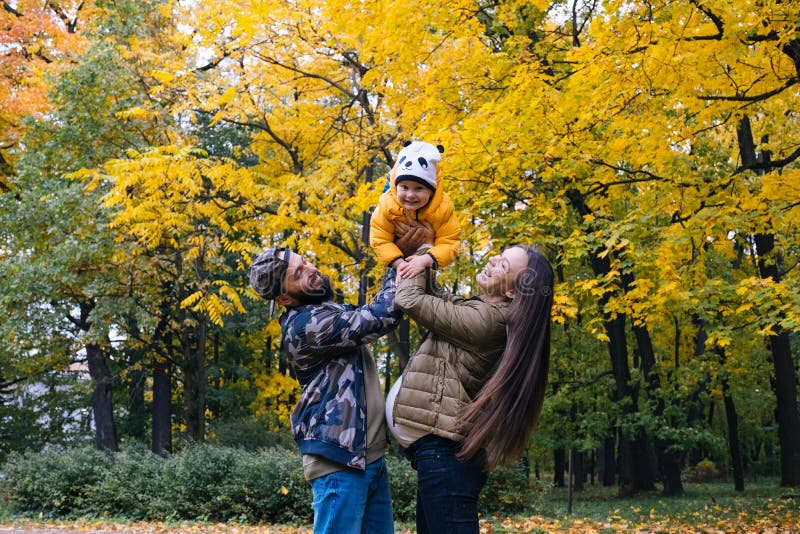 Famiglia felice all'aperto La madre, il padre ed il bambino sull'autunno camminano nel parco fotografia stock Famiglia felice all'aperto La madre, il padre ed il bambino sull'autunno camminano nel parco fotografia stock