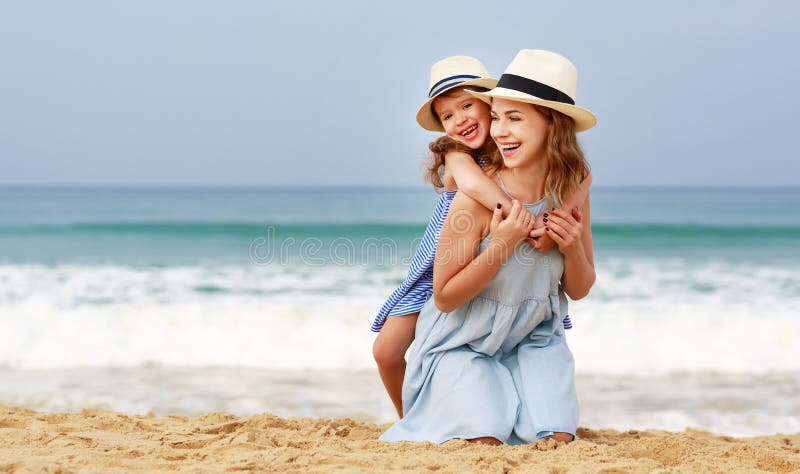 Famiglia felice alla spiaggia abbraccio della figlia del bambino e della madre in mare