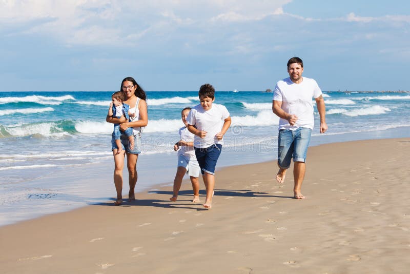 Famiglia felice che cammina sulla spiaggia immagini stock Famiglia felice che cammina sulla spiaggia immagini stock