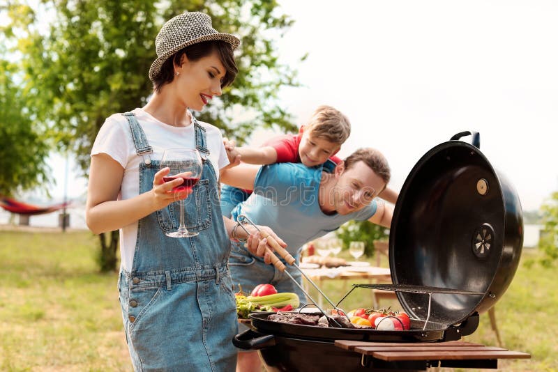 Famiglia felice che ha barbecue con la griglia moderna immagini stock libere da diritti Famiglia felice che ha barbecue con la griglia moderna immagini stock libere da diritti