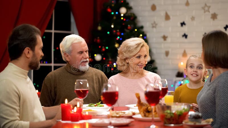 Famiglia felice che ha cena tradizionale di natale, bambina che racconta le storie divertenti immagini stock Famiglia felice che ha cena tradizionale di natale, bambina che racconta le storie divertenti immagini stock