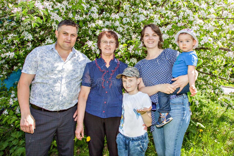 Famiglia felice che spende tempo all'aperto un giorno di estate soleggiato mamma, papà, nonna e due ragazzi immagine stock libera da diritti Famiglia felice che spende tempo all'aperto un giorno di estate soleggiato mamma, papà, nonna e due ragazzi immagine stock libera da diritti