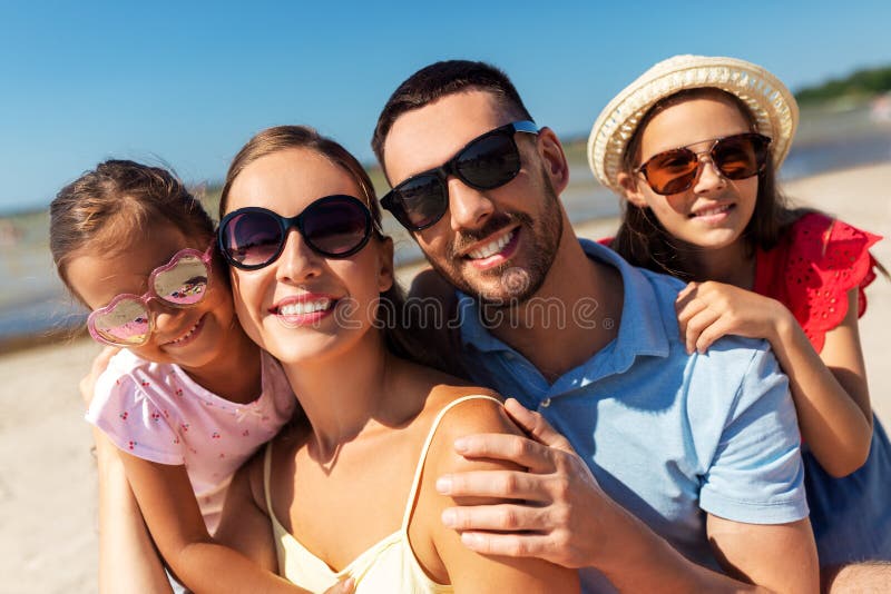 Famiglia felice con gli occhiali da sole sulla spiaggia d'estate