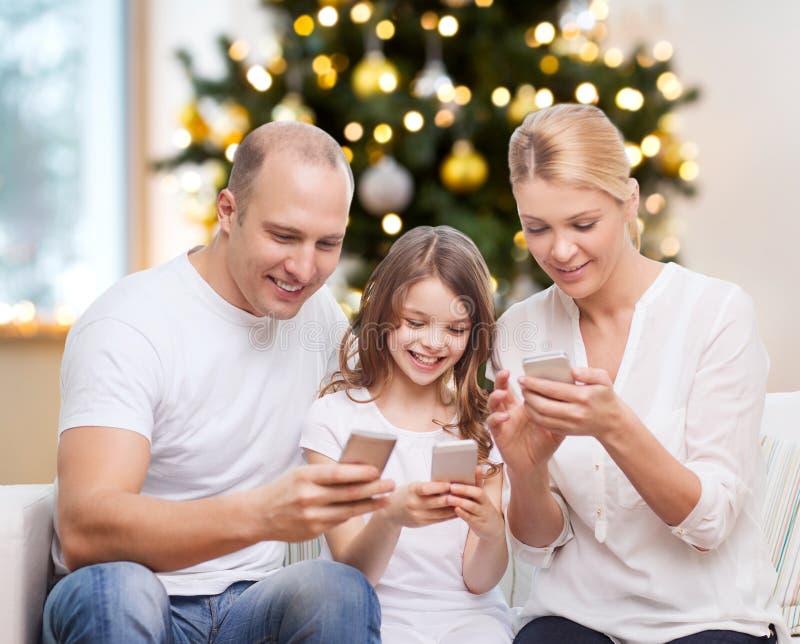 Famiglia felice con gli smartphone a casa a natale