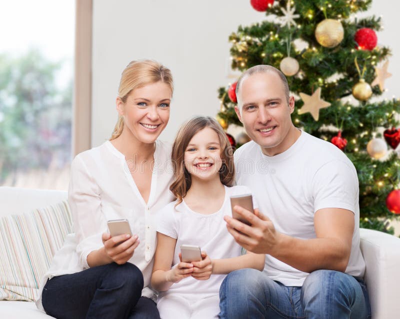 Famiglia felice con gli smartphone a casa a natale