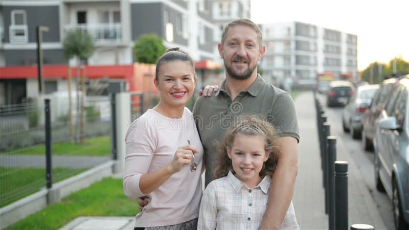 Famiglia felice con i bambini che stanno le chiavi all'aperto della tenuta di grande casa di campagna Coppie di lusso sorridenti