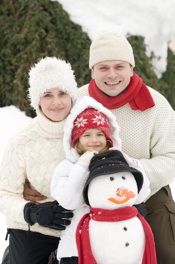Famiglia felice con il pupazzo di neve fotografia stock libera da diritti Famiglia felice con il pupazzo di neve fotografia stock libera da diritti