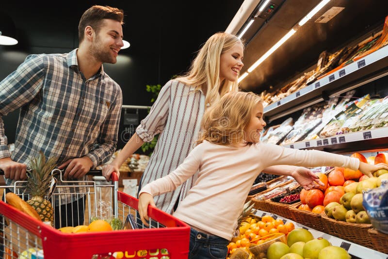 Famiglia felice con l'alimento d'acquisto del carrello e del bambino fotografia stock libera da diritti Famiglia felice con l'alimento d'acquisto del carrello e del bambino fotografia stock libera da diritti