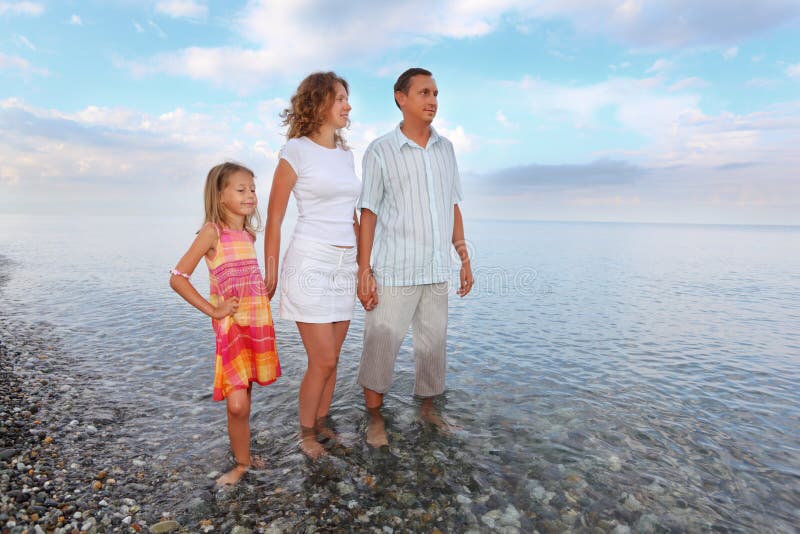 Famiglia felice con la ragazza che si leva in piedi ginocchio-profonda in mare fotografie stock libere da diritti Famiglia felice con la ragazza che si leva in piedi ginocchio-profonda in mare fotografie stock libere da diritti