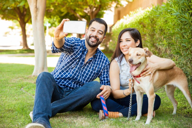 Famiglia felice con un cane che prende selfie fotografia stock libera da diritti Famiglia felice con un cane che prende selfie fotografia stock libera da diritti
