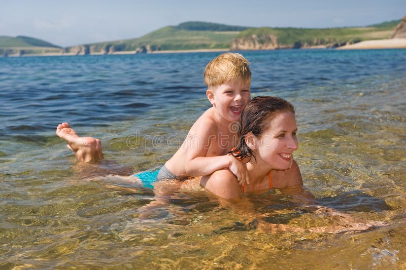 Famiglia felice della madre con il bambino che gioca nelle onde fotografia stock libera da diritti Famiglia felice della madre con il bambino che gioca nelle onde fotografia stock libera da diritti