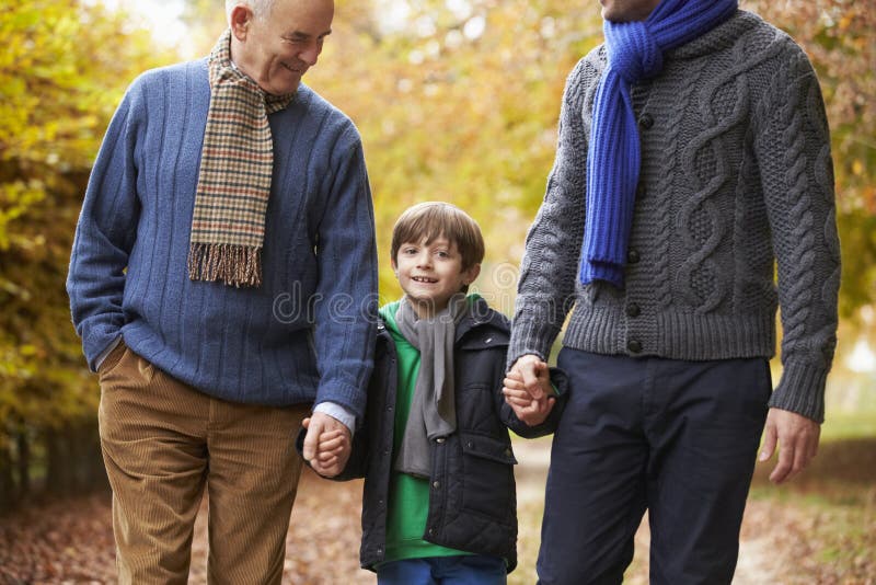 Famiglia maschio della generazione di Multl che cammina lungo Autumn Path immagine stock Famiglia maschio della generazione di Multl che cammina lungo Autumn Path immagine stock