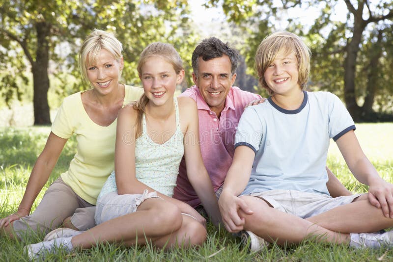 Famiglia Medio Evo che si siede nel campo in campagna fotografia stock Famiglia Medio Evo che si siede nel campo in campagna fotografia stock