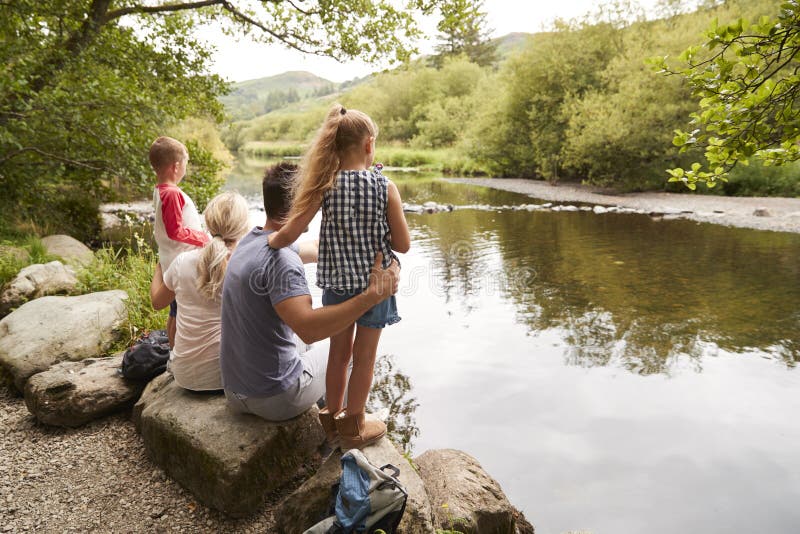 Famiglia sull'aumento che guarda fuori sopra il fiume nel distretto BRITANNICO del lago