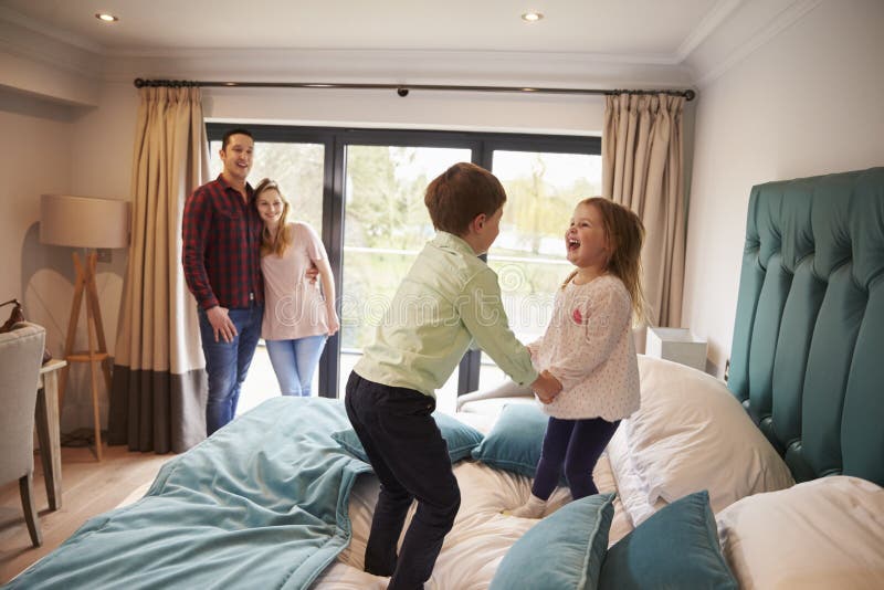 Famiglia sulla vacanza con i bambini che giocano sul letto dell'hotel fotografie stock Famiglia sulla vacanza con i bambini che giocano sul letto dell'hotel fotografie stock