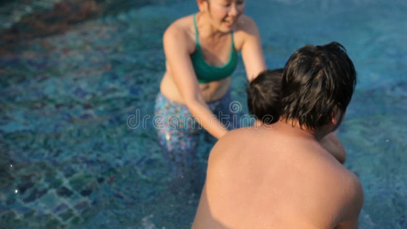 Familia asiatică se joacă cu fericirea relaxându-se în bazinul de apă stock video
