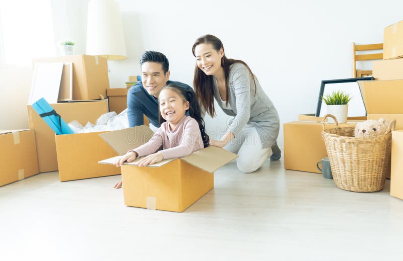 Familia asiática joven feliz de tres que se divierten que se mueve con cardboa