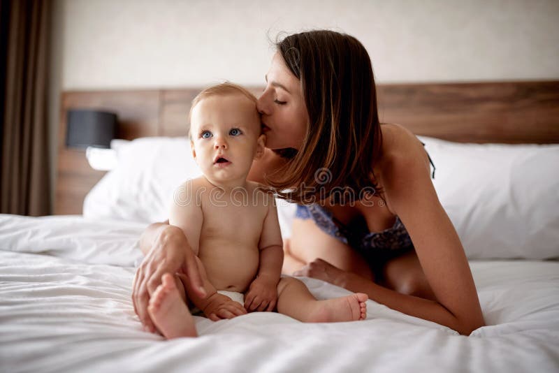 Familia cariñosa feliz Mime a besar a su hijo del niño en la cama fotografía de archivo Familia cariñosa feliz Mime a besar a su hijo del niño en la cama fotografía de archivo