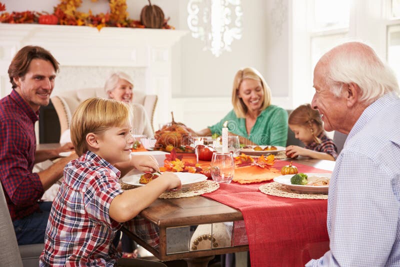 Familia con los abuelos que disfrutan de la comida de la acción de gracias en la tabla