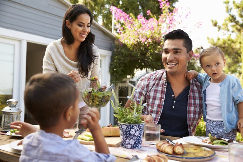 Familia en casa que come la comida al aire libre en jardín junto