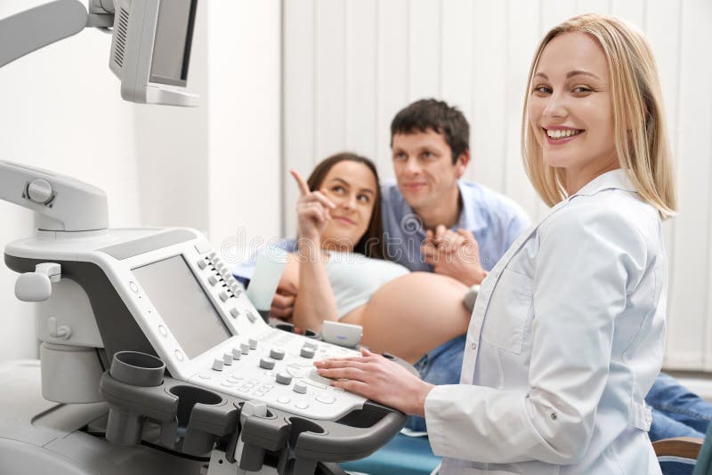 Familia en la diagnosis del ultrasonido, sonrisa del doctor, presentando fotografía de archivo libre de regalías Familia en la diagnosis del ultrasonido, sonrisa del doctor, presentando fotografía de archivo libre de regalías
