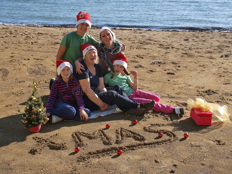 Familia en las canciones de la Navidad del canto de la playa fotografía de archivo Familia en las canciones de la Navidad del canto de la playa fotografía de archivo