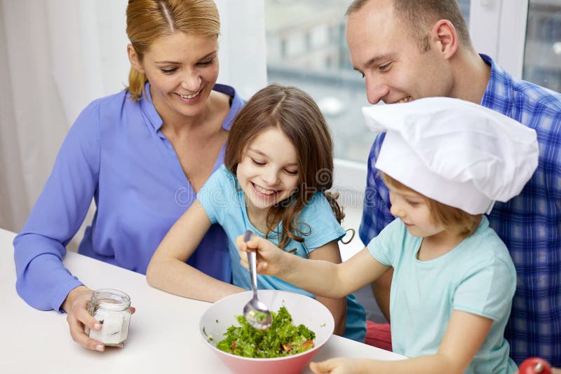 Familia feliz con dos niños que cocinan en casa imagen de archivo Familia feliz con dos niños que cocinan en casa imagen de archivo