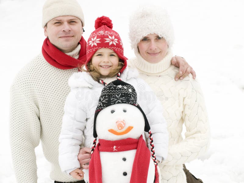 Familia feliz con el muñeco de nieve fotografía de archivo Familia feliz con el muñeco de nieve fotografía de archivo