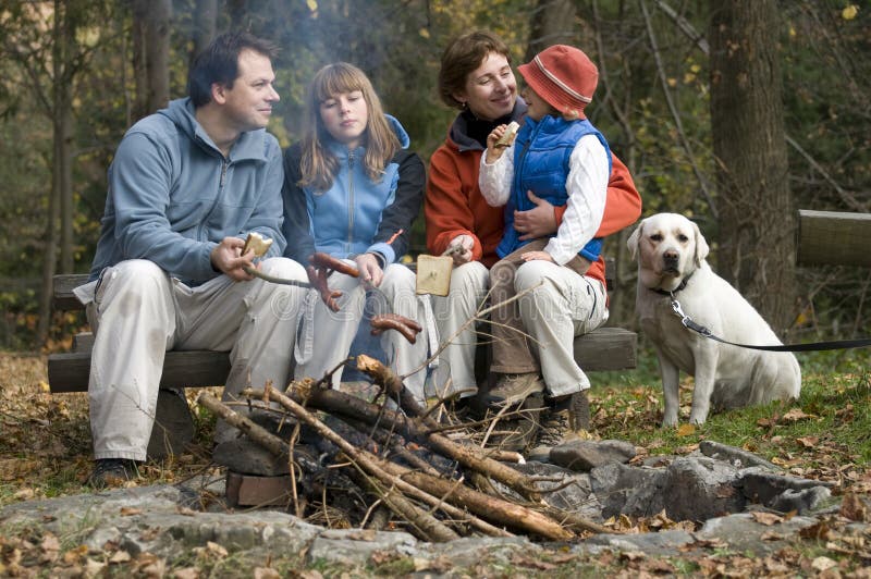 Familia feliz con el perro cerca de la hoguera fotos de archivo libres de regalías Familia feliz con el perro cerca de la hoguera fotos de archivo libres de regalías