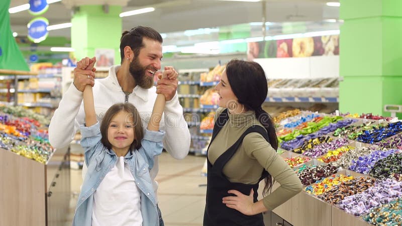 Familia feliz con un caramelo y los dulces de la compra del niño en el supermercado Cámara lenta metrajes Familia feliz con un caramelo y los dulces de la compra del niño en el supermercado Cámara lenta metrajes