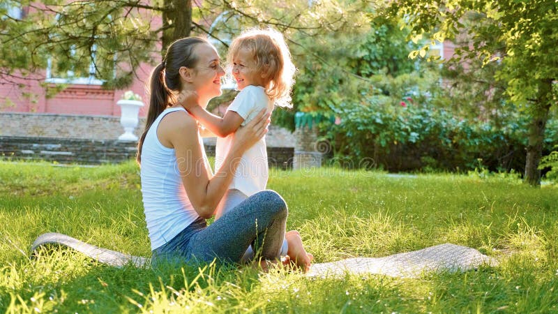 Familia feliz de madre deportiva joven y pequeña de hija linda que se divierten al aire libre imagen de archivo libre de regalías Familia feliz de madre deportiva joven y pequeña de hija linda que se divierten al aire libre imagen de archivo libre de regalías