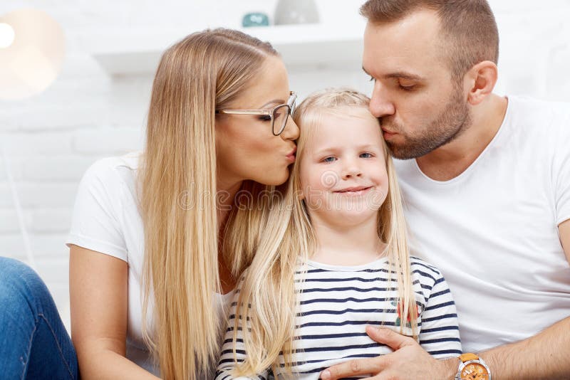 Familia feliz en casa en el amor que besa al niño foto de archivo Familia feliz en casa en el amor que besa al niño foto de archivo
