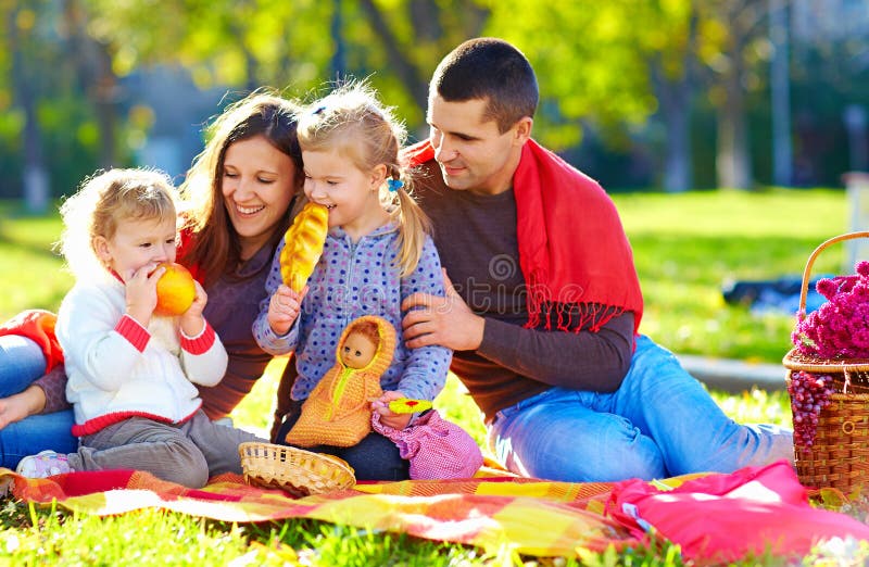 Familia feliz en comida campestre del otoño en parque